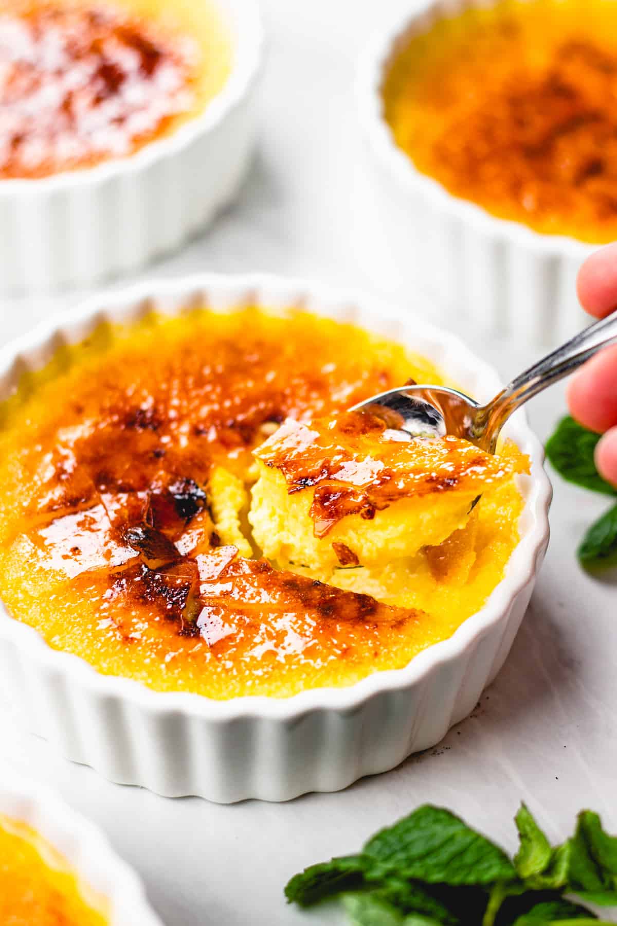 Creme brulee in a white ramekin with a spoon.