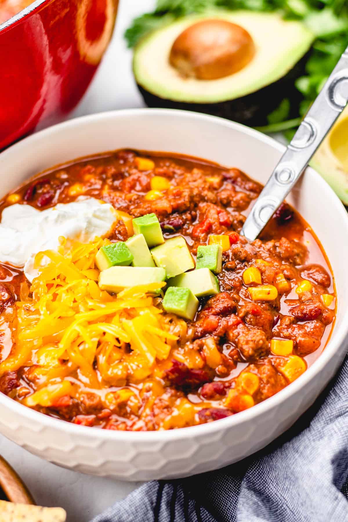 beef chilli, topped with sour cream, cheese, and avocado in a bowl.