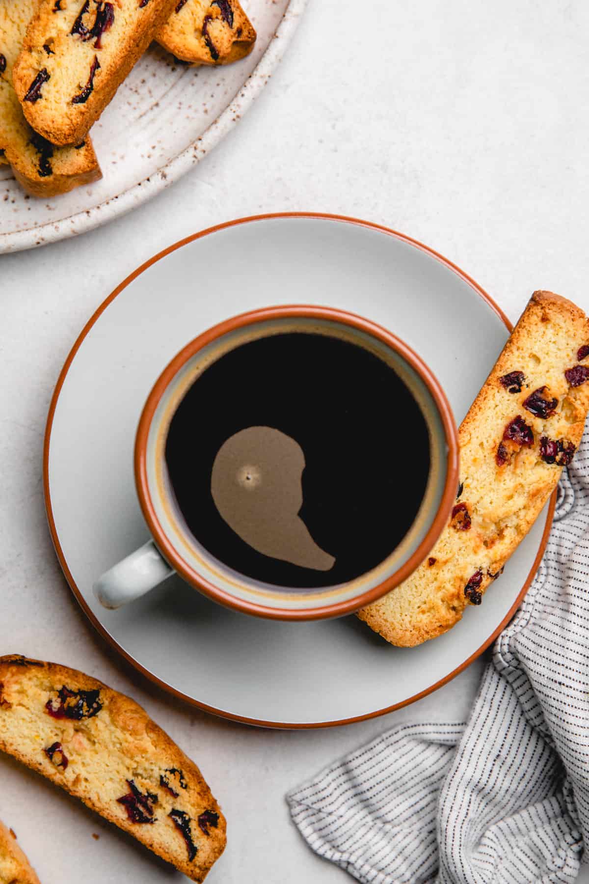 A cup of coffee with Orange Cranberry Biscotti.