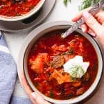 Borscht soup in a bowl, topped with sour cream and fresh dill.