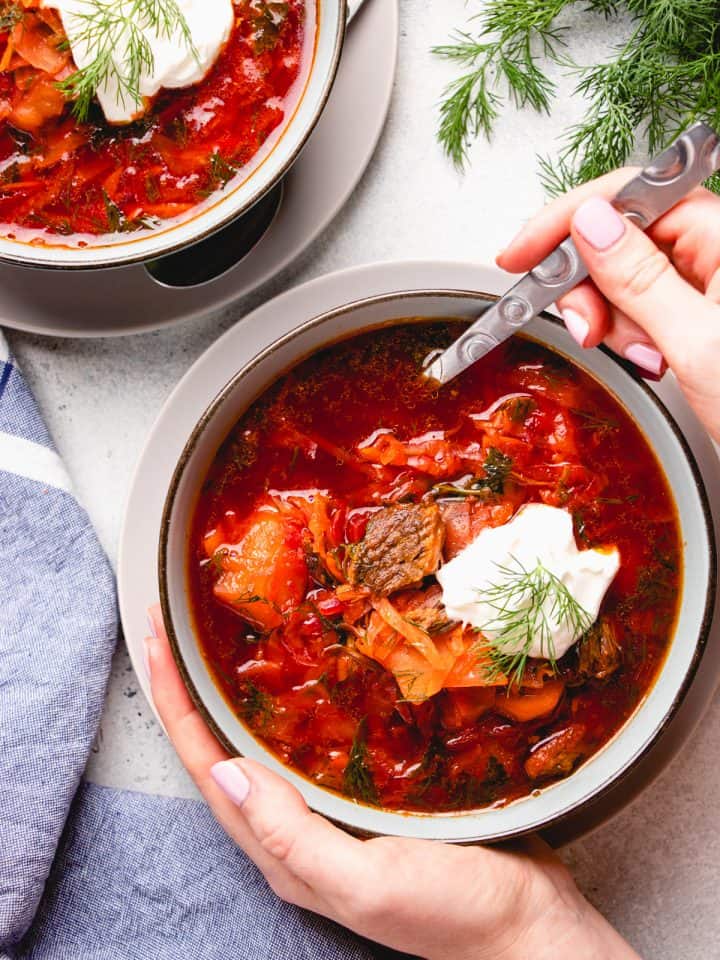 Borscht soup in a bowl, topped with sour cream and fresh dill.