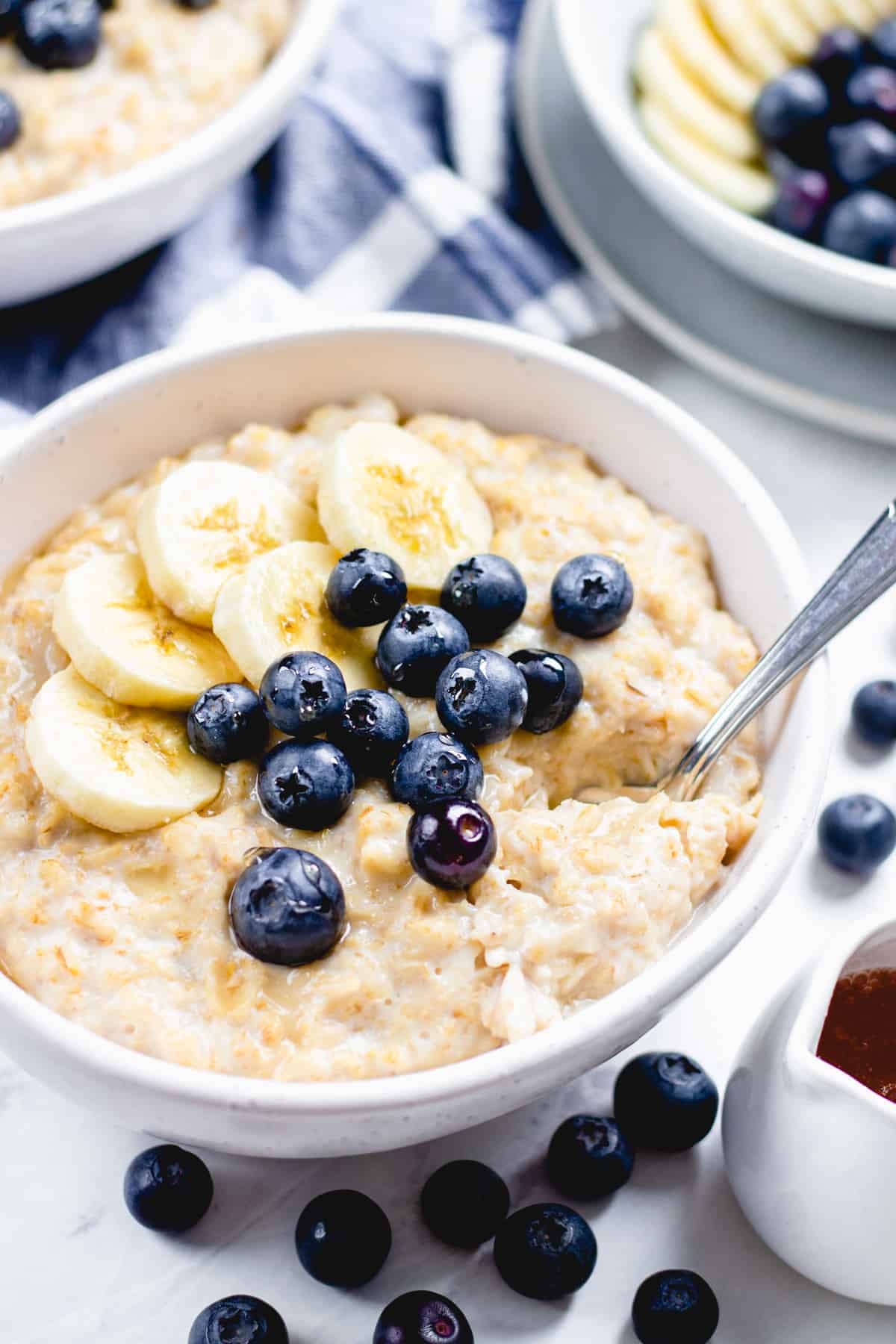 Oatmeal , topped with bananas and blueberries in a bowl.