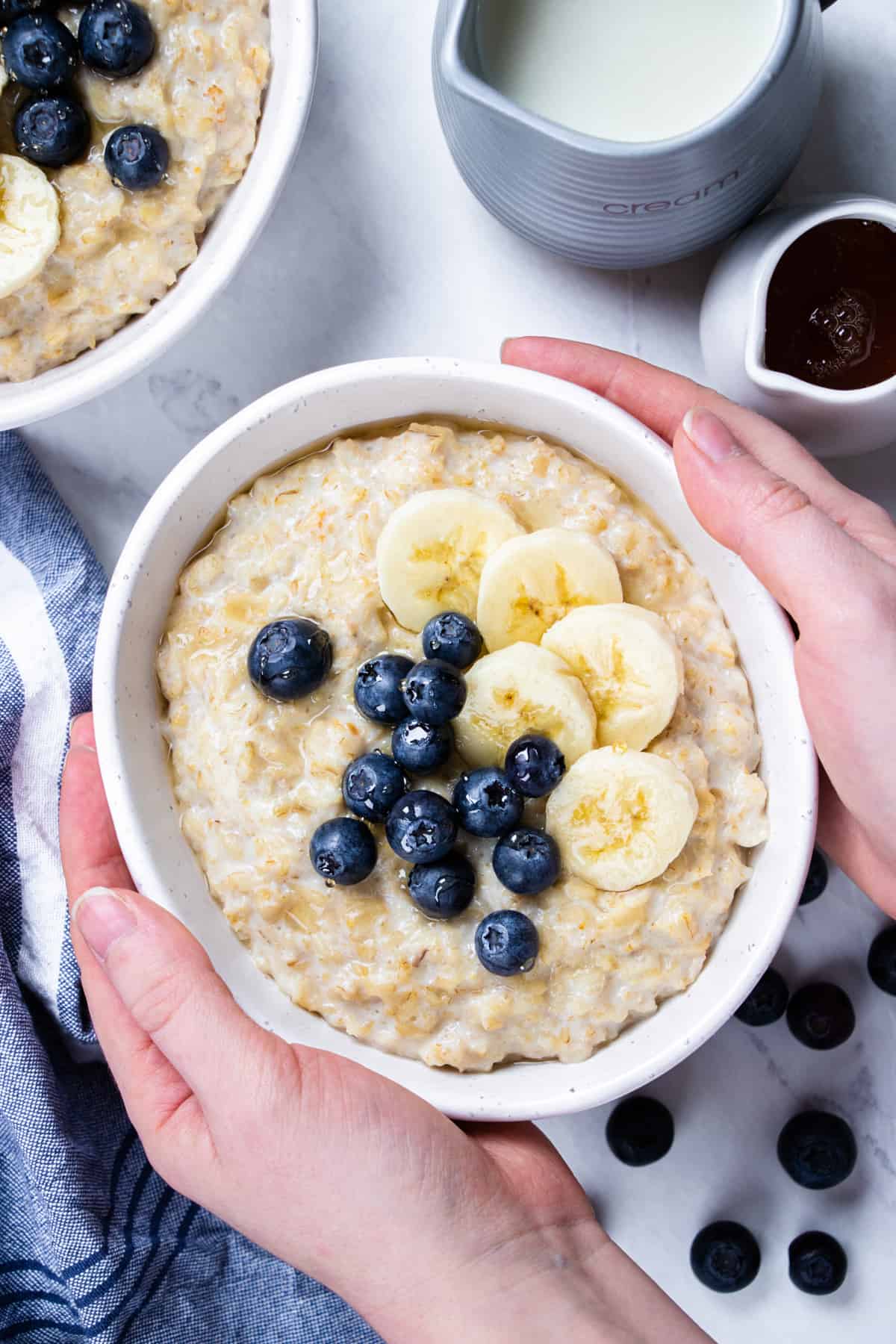 Oatmeal , topped with bananas and blueberries in a bowl.