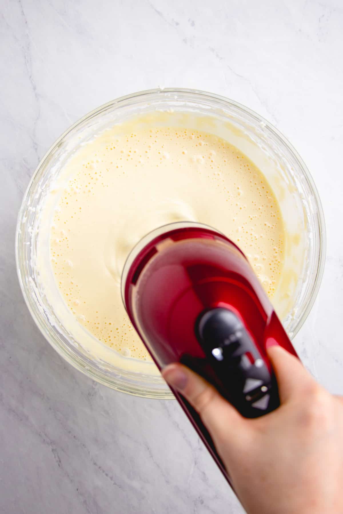 Mixing cheesecake filling with a hand mixer.