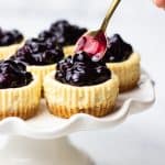 Topping mini cheesecakes with blueberry sauce.