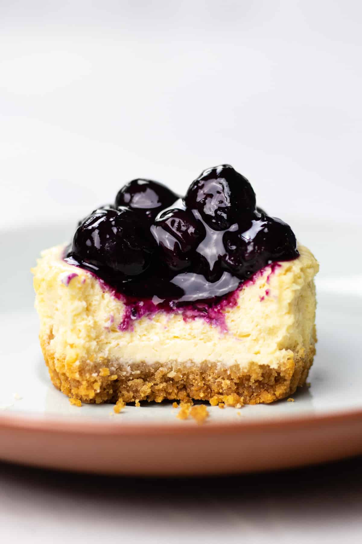 A bit shot os a mini cheesecake, topped with blueberry sauce.
