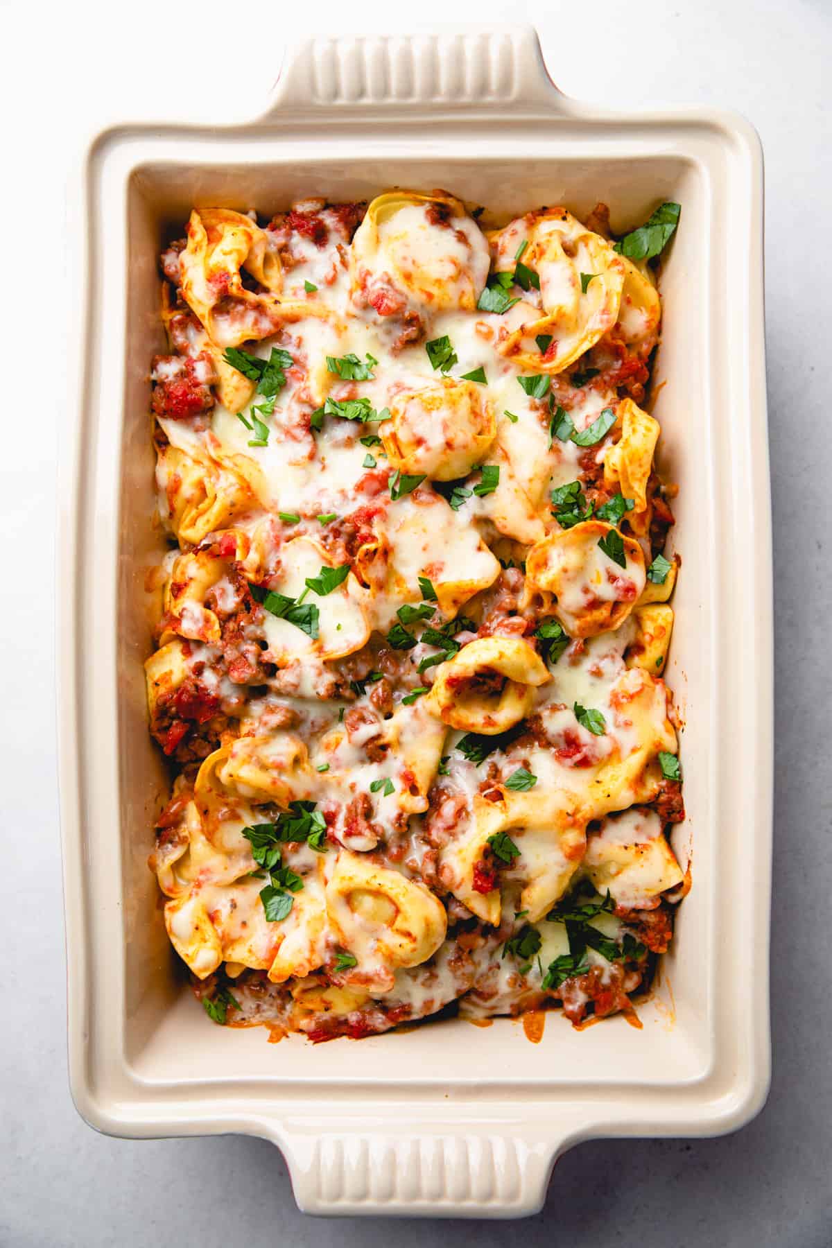 Tortellini with meat sauce and melted cheese in a baking dish.