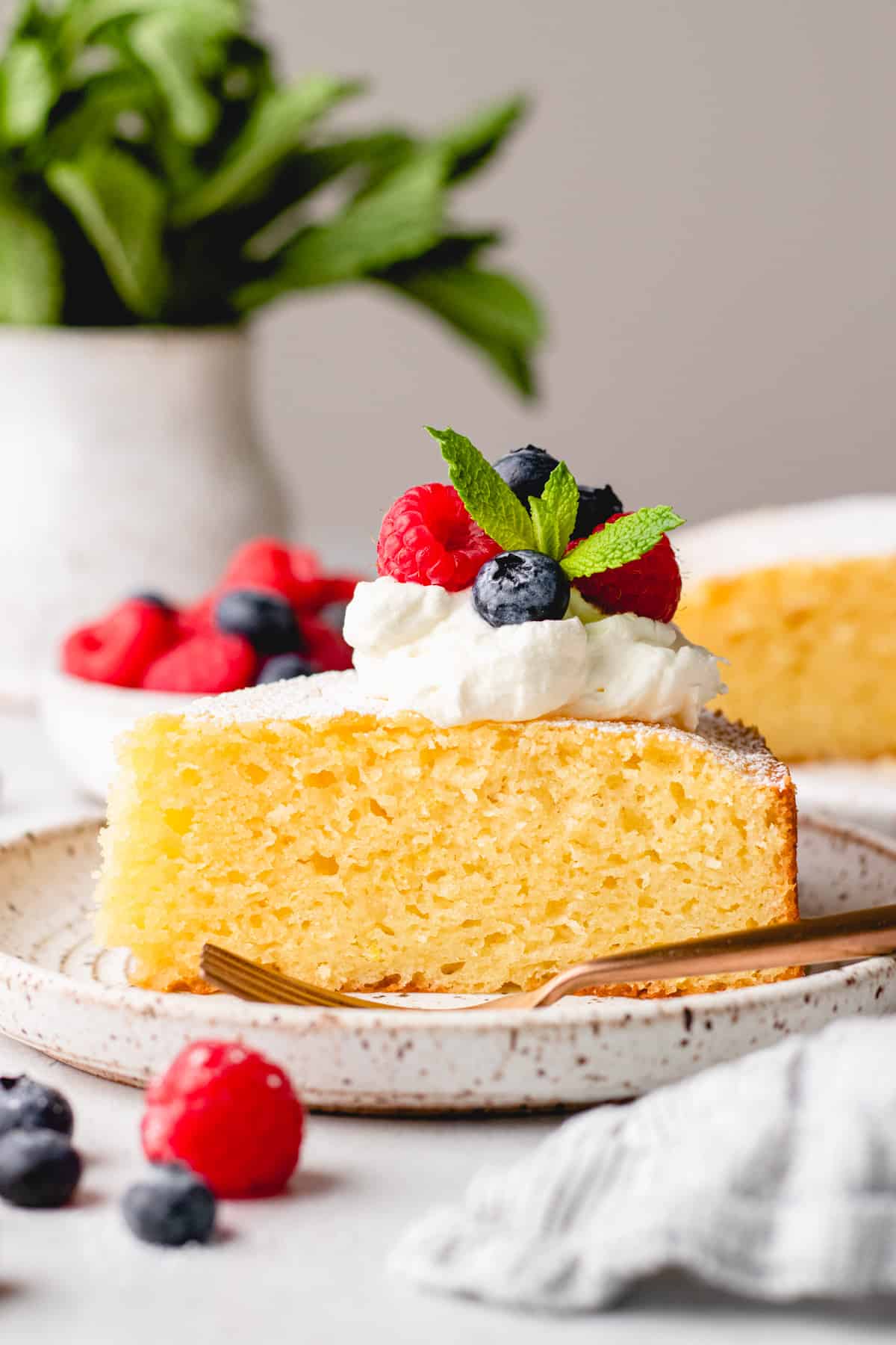 A slice of Italian Lemon Ricotta Cake on a plate with a fork and fresh berries.