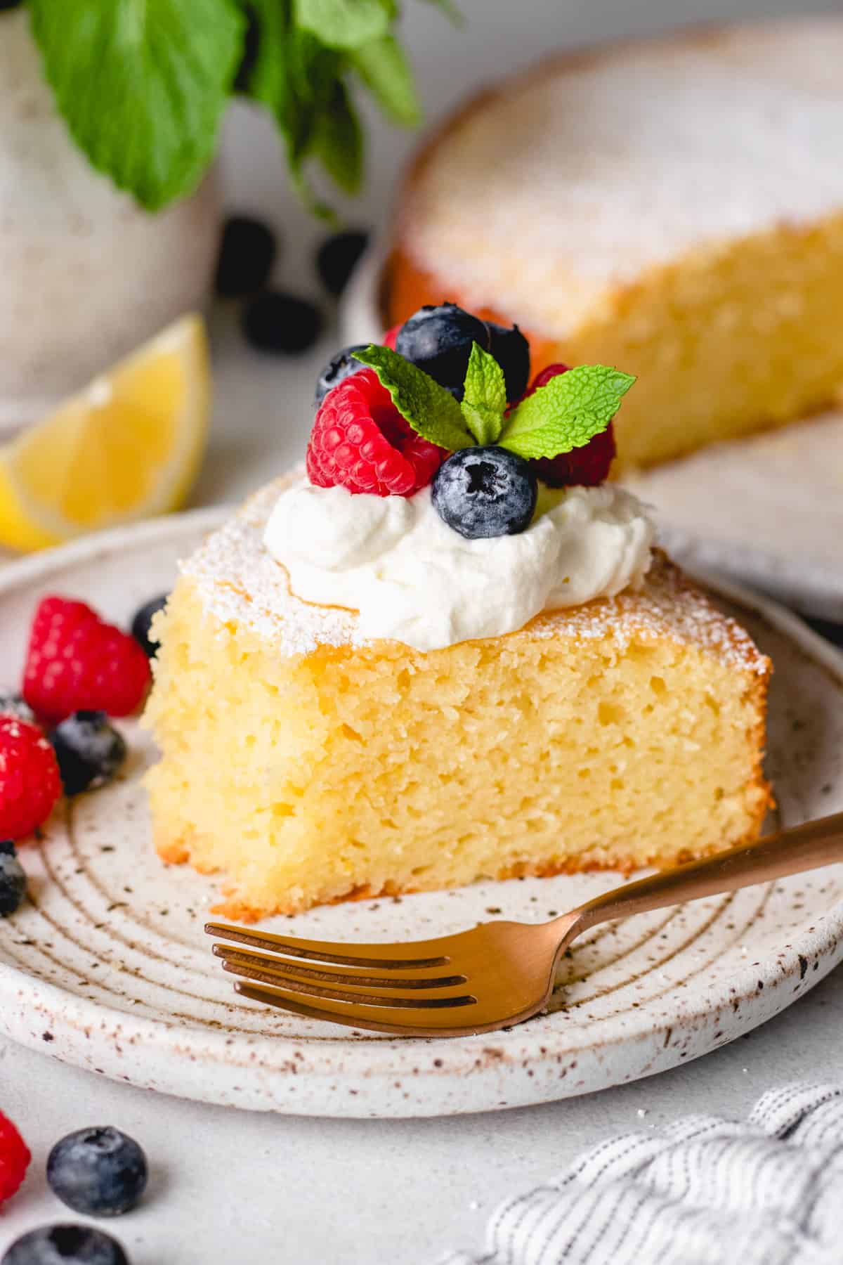 A slice of Italian Lemon Ricotta Cake on a plate with a fork and fresh berries.