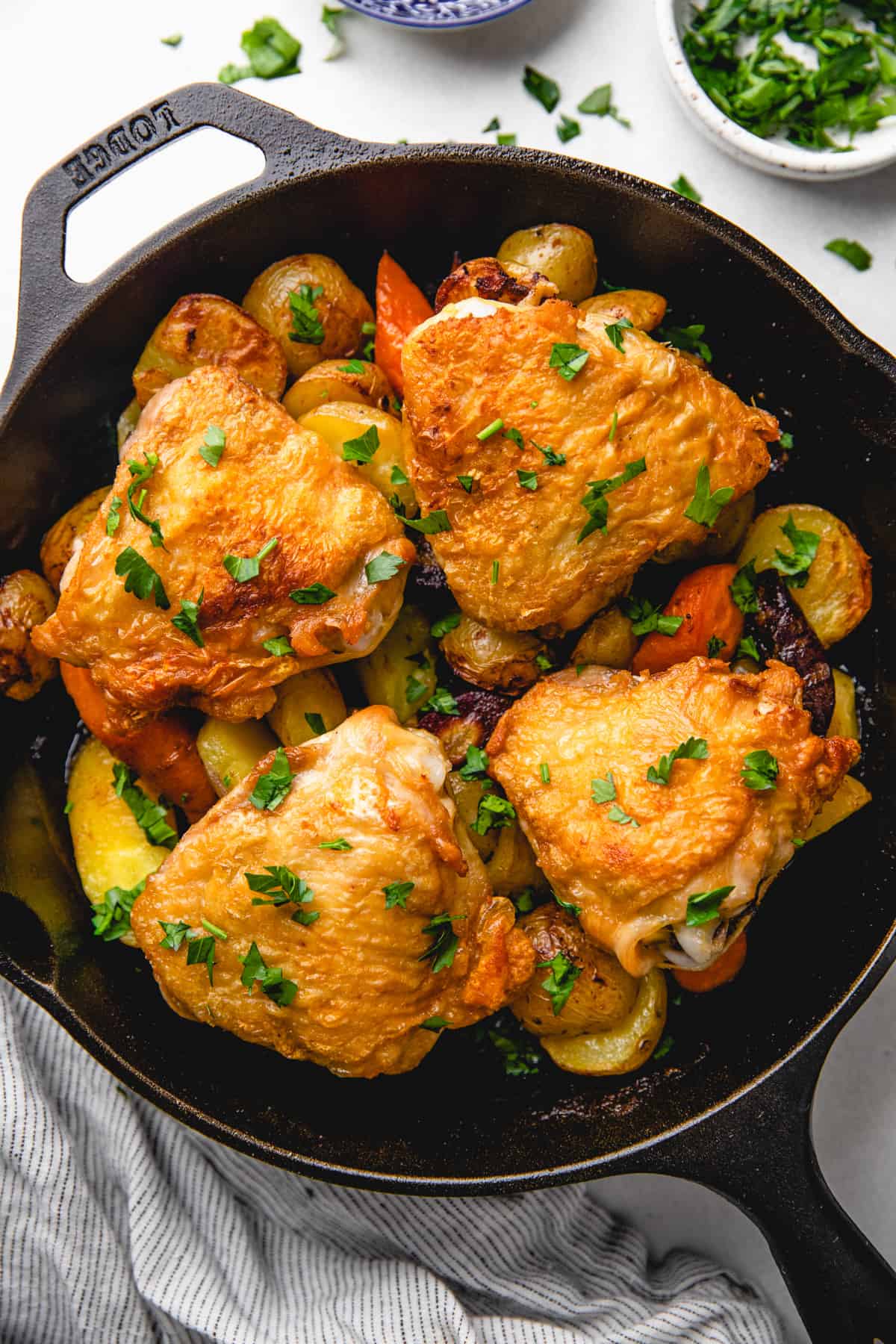 Roasted chicken thighs over vegetables in a cast iron skillet.
