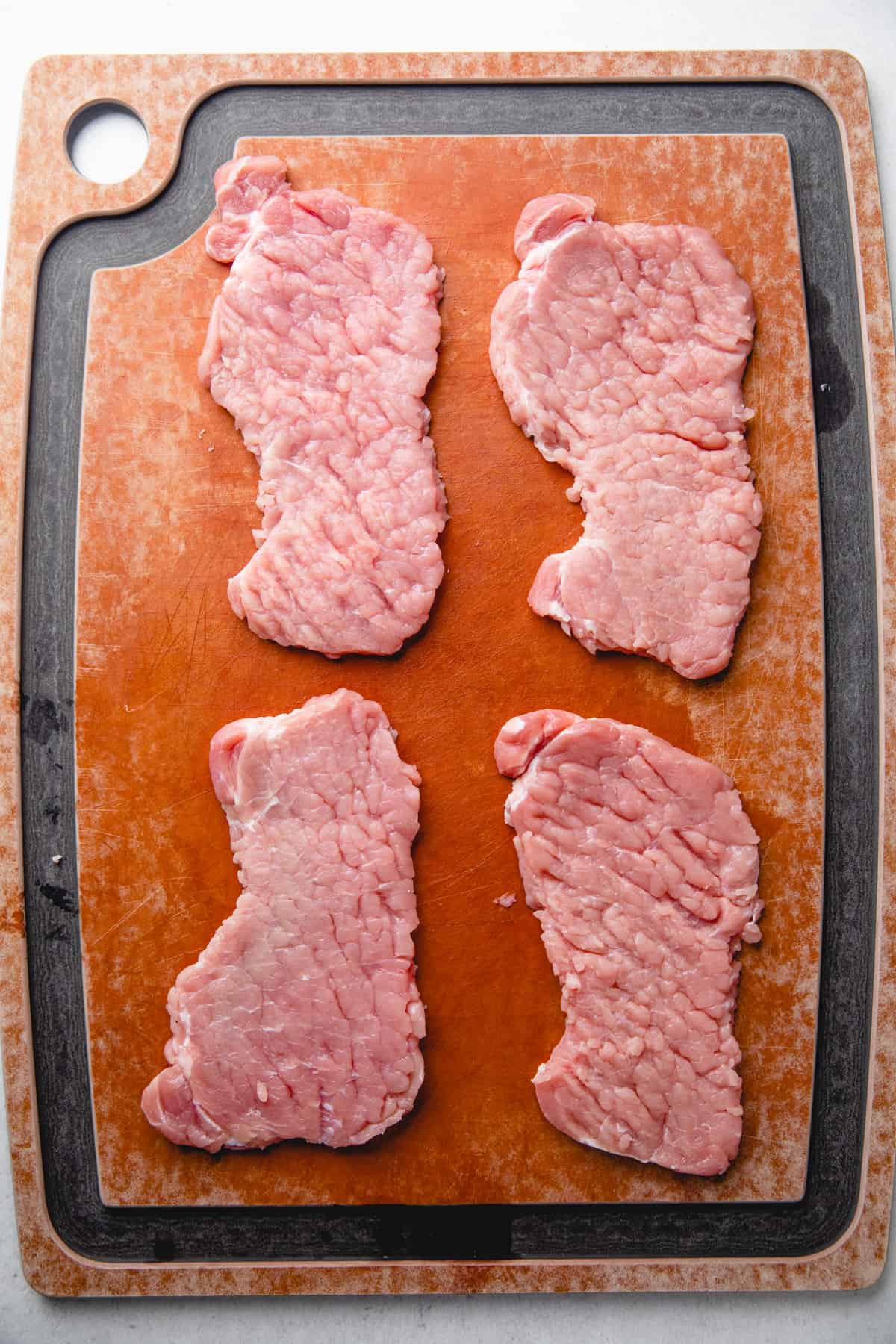 Pounded pork chops on a cutting board.