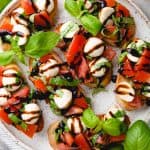 Bread slices, topped with diced tomatoes, mozzarella, and basil, and drizzled with balsamic glaze.