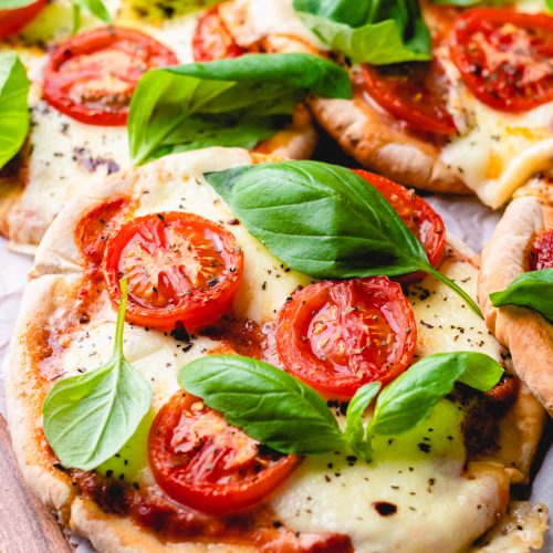 Mini Margherita pizza made with pita bread, topped with cheese, tomatoes, and basil.