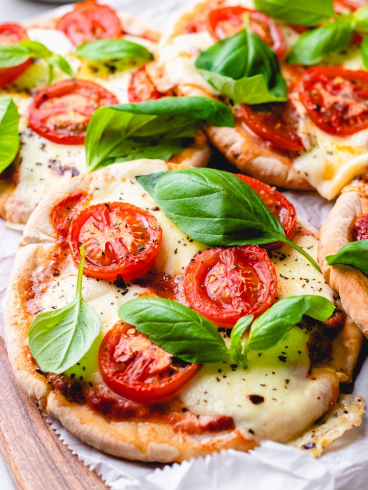 Mini Margherita pizza made with pita bread, topped with cheese, tomatoes, and basil.
