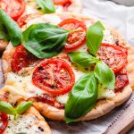 Mini Margherita pizza made with pita bread, topped with cheese, tomatoes, and basil.