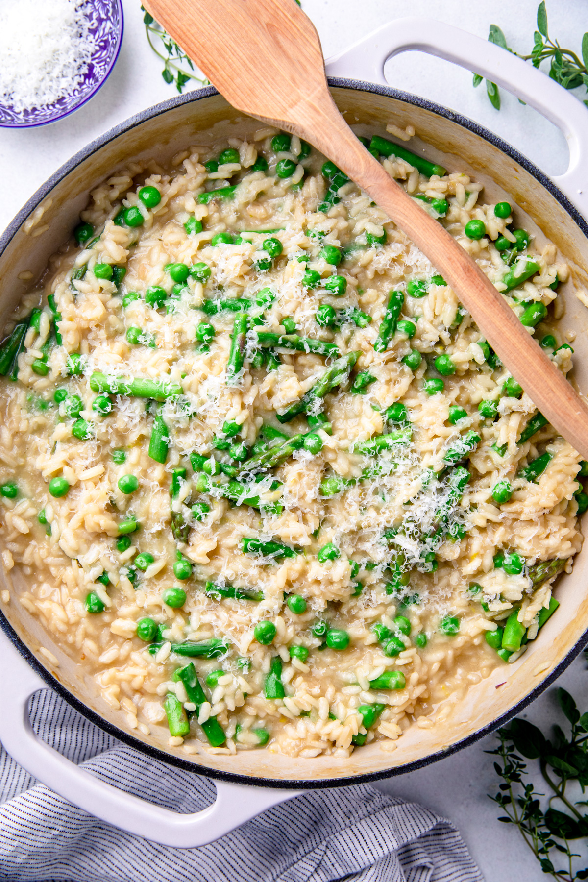 Risotto with peas and asparagus in a pot with a wooden spoon.