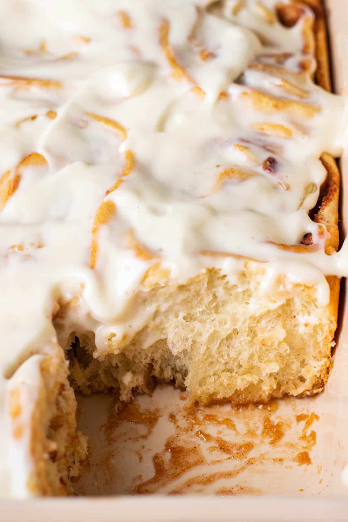 Apple Pie Cinnamon Rolls topped with cream cheese frosting in a baking dish.