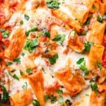Pasta in tomato sauce with bell pepper, zucchini, spinach, and topped with cheese..