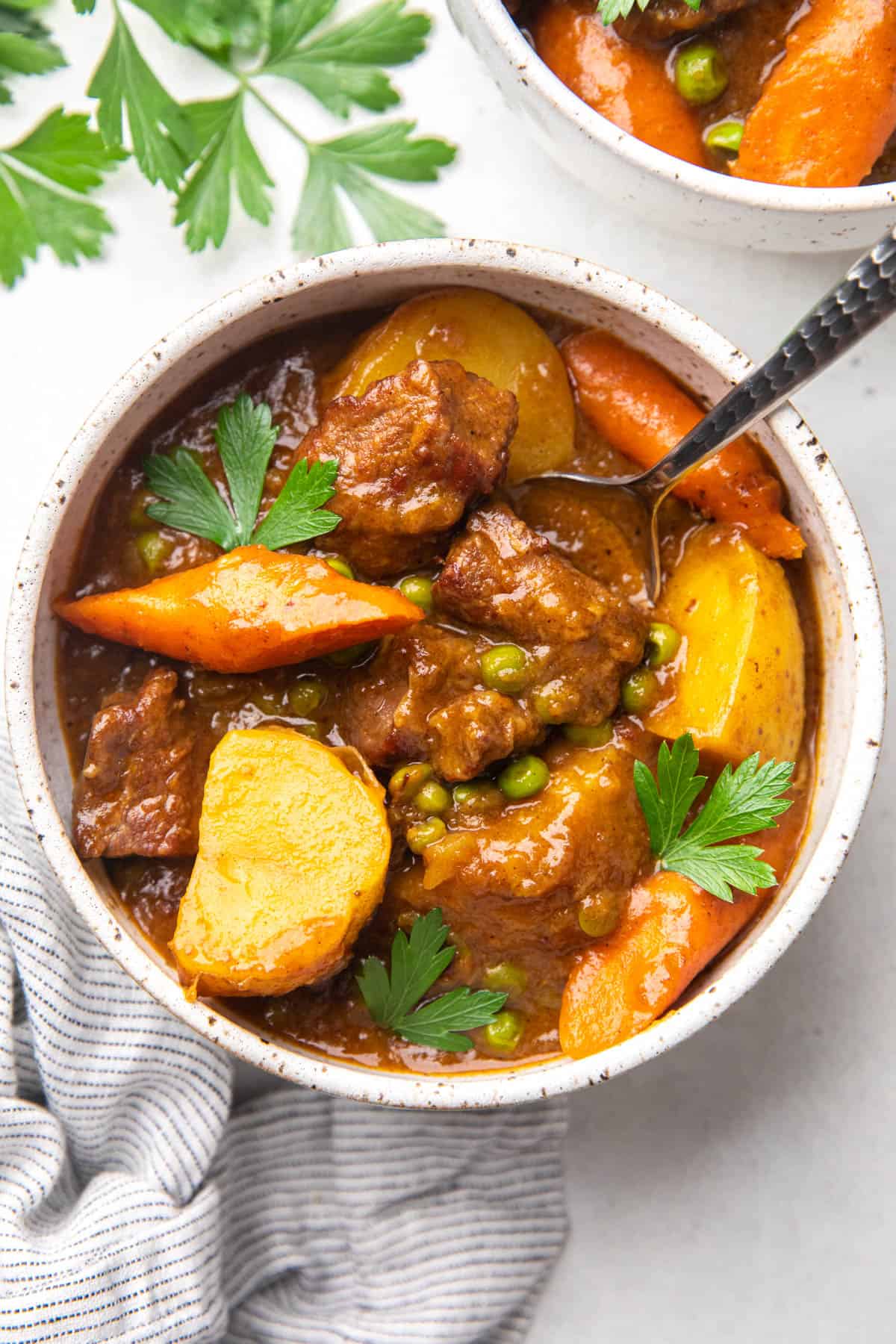 Stew with beef tips, potatoes, carrots, and peas in a bowl.