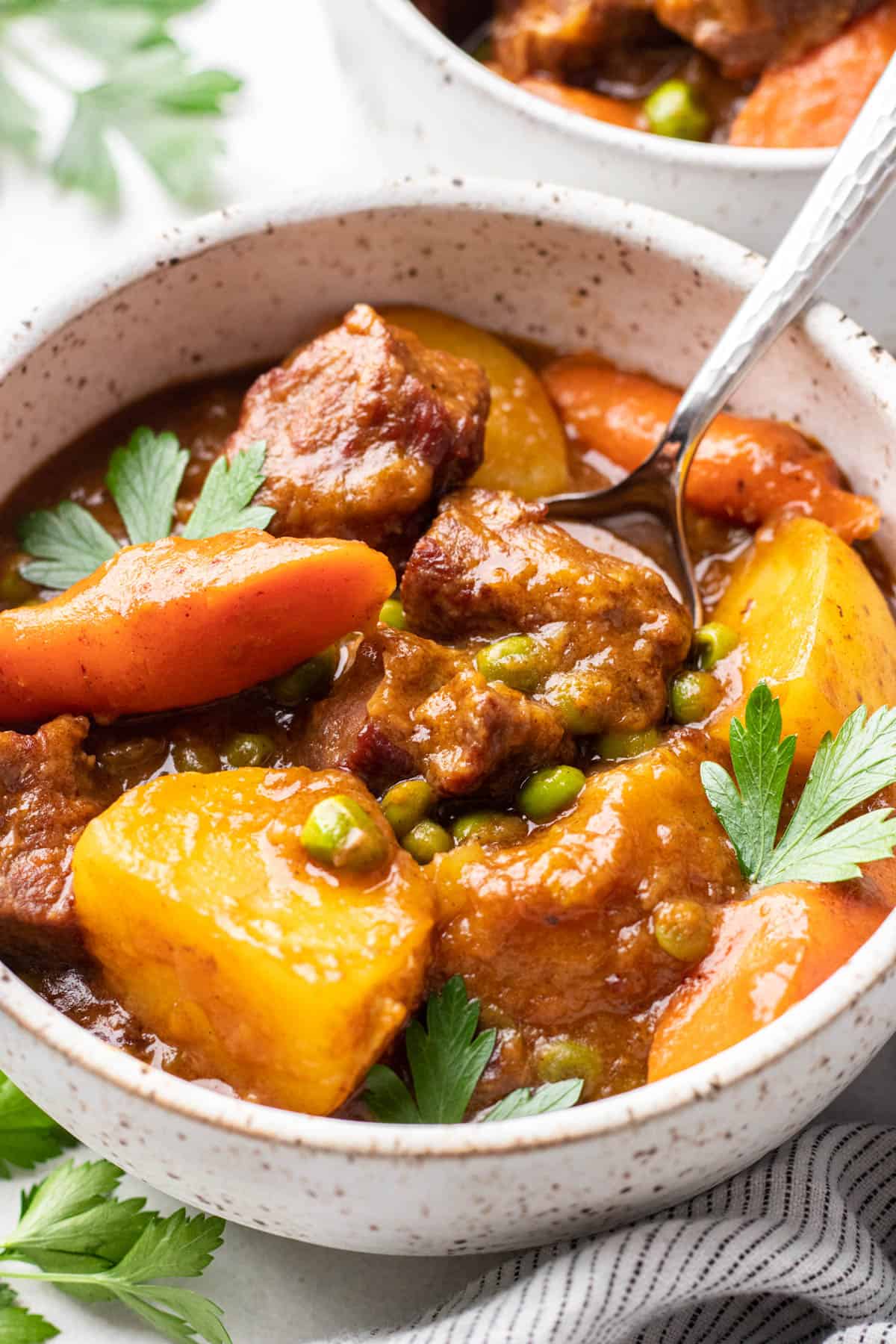 Stew with beef tips, potatoes, carrots, and peas in a bowl.