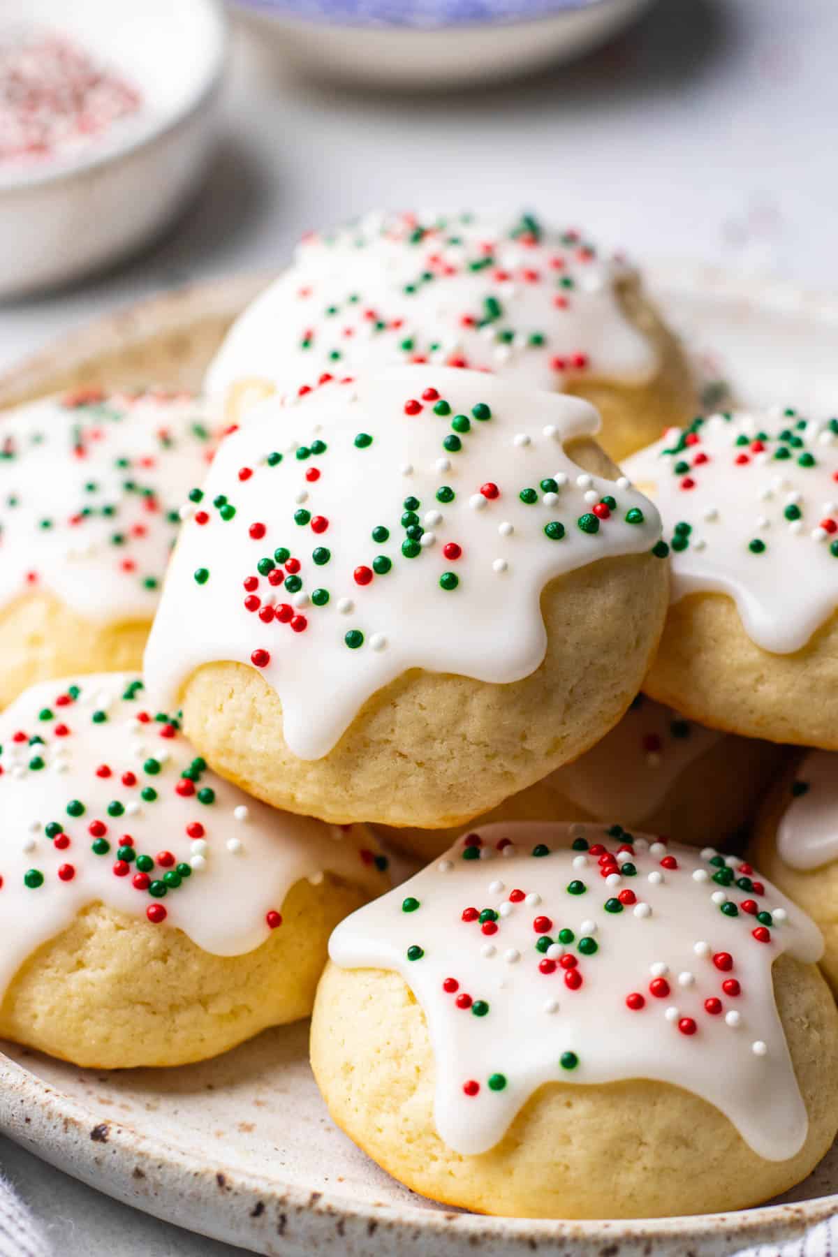 Sour Cream Cookies, topped with sugar icing and sprinkles on a plate.