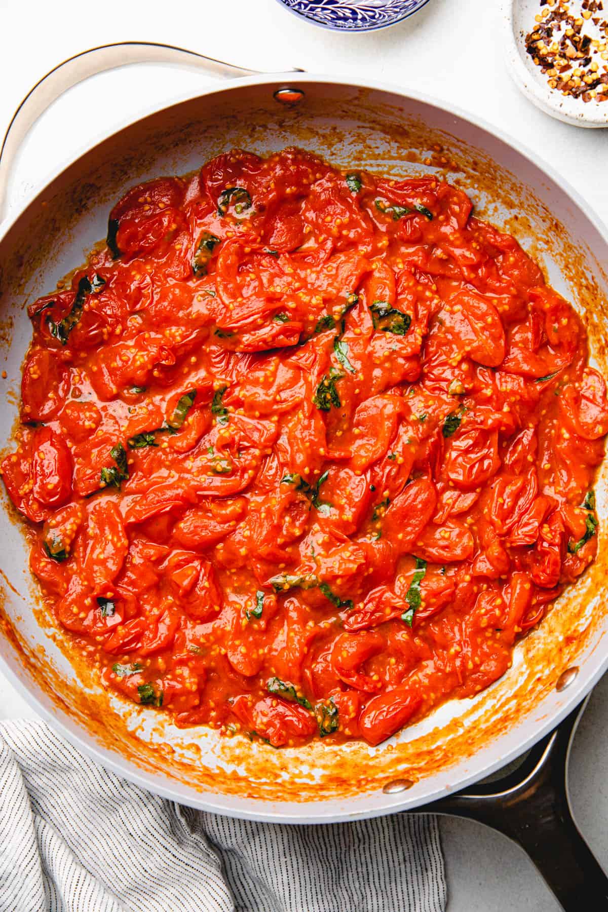 Cherry tomato sauce with basil in a large pan.