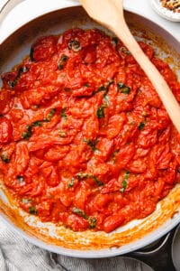 Cherry tomato sauce with basil in a large pan.