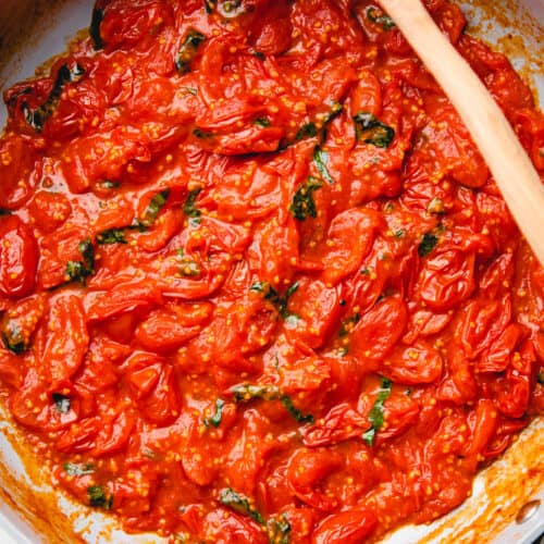 Cherry tomato sauce with basil in a large pan.