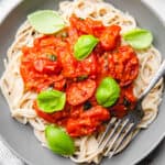 Spaghetti, topped with cherry tomato sauce and basil, in a bowl.