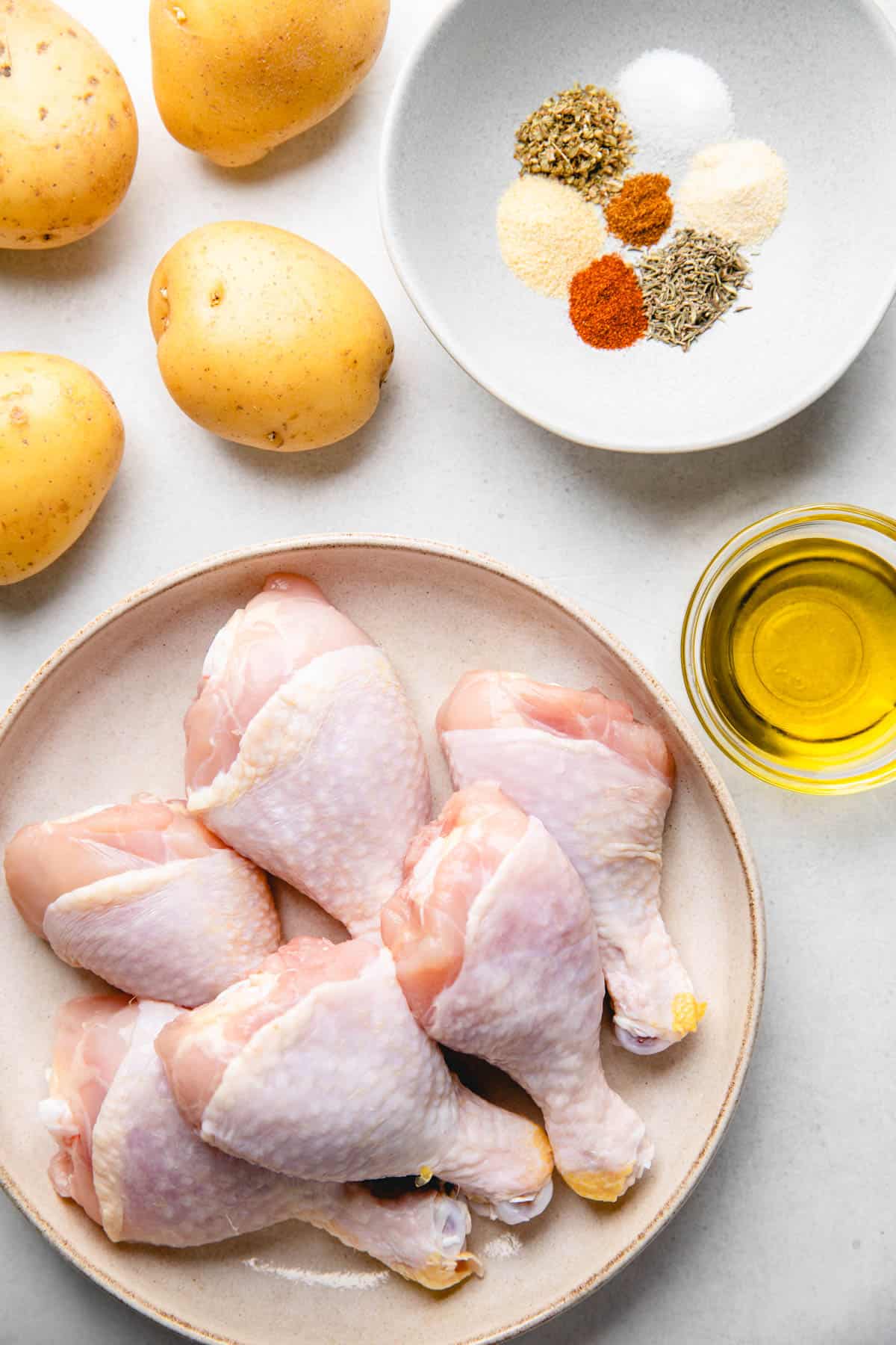 Ingredients to make oven baked chicken legs with potatoes.