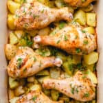 Chicken drumsticks with potatoes in a baking dish.