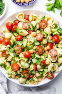 Salad, made with pasta, chickpeas, cherry tomatoes, cucumbers, and herbs.