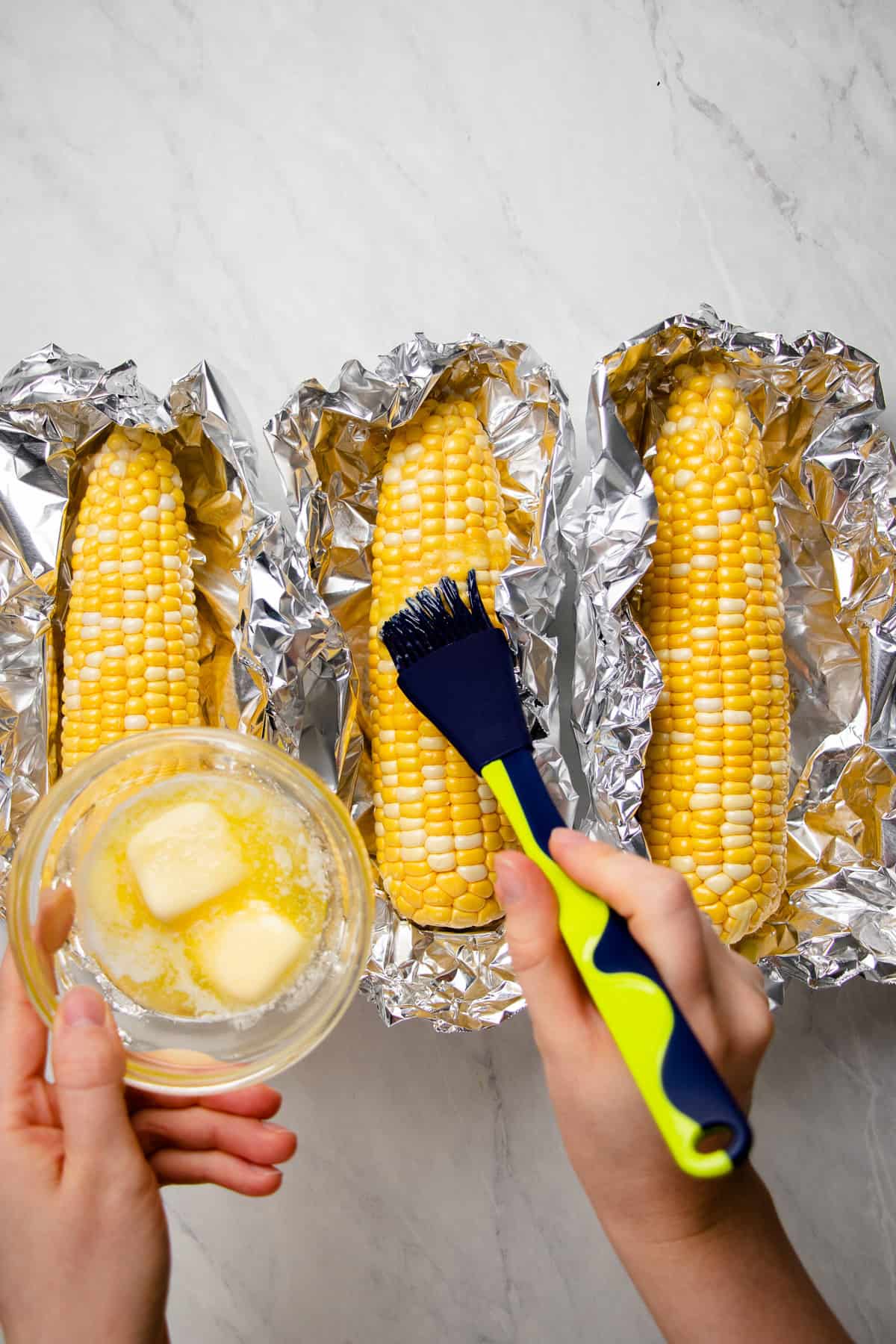 Brushing corn on the bob with melted butter.
