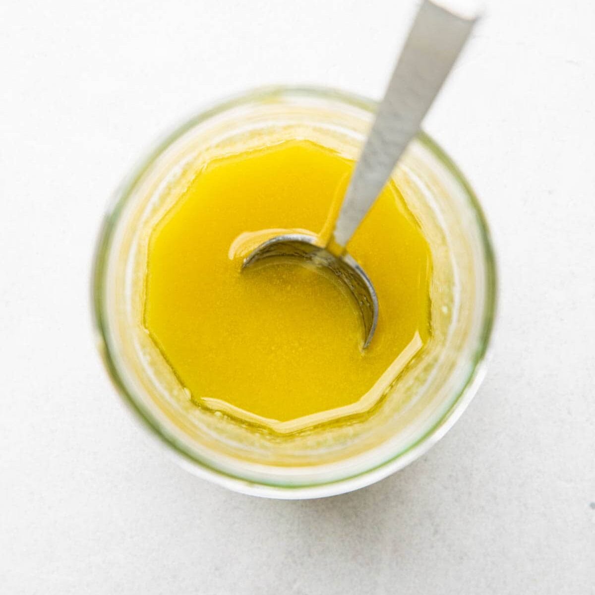 Maple Dijon Vinaigrette in a jar with a spoon.
