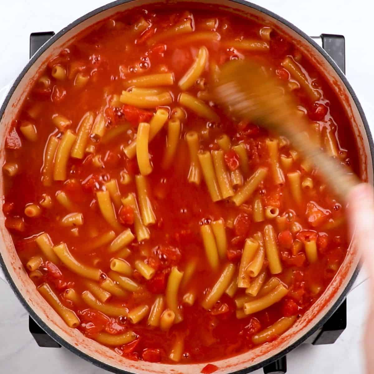Stirring ziti in tomato sauce.